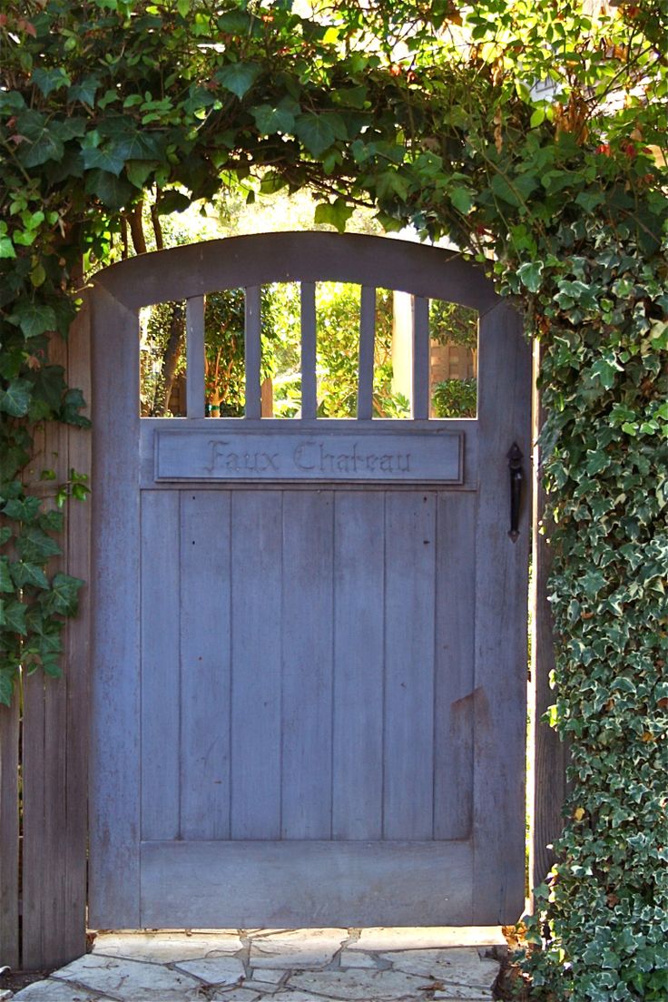 an old wooden gate is surrounded by greenery