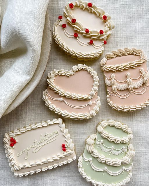 decorated cookies in the shape of heart shaped cakes on a white tablecloth with red beads