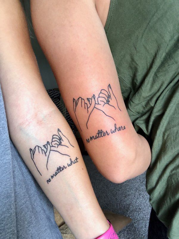 two people with matching tattoos on their arms, one holding the other's hand