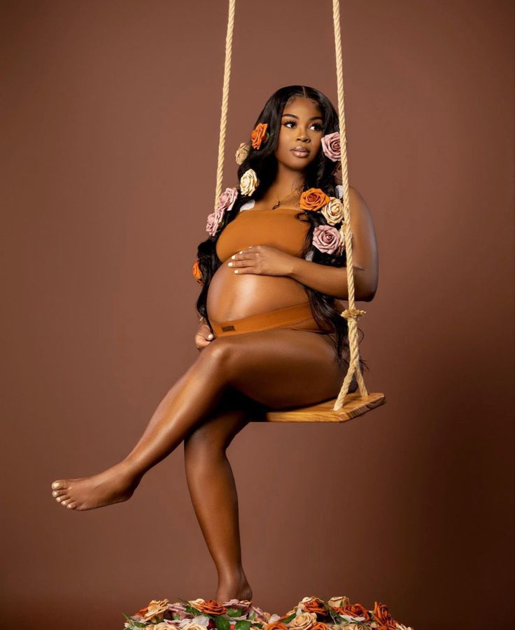 a pregnant woman sitting on a swing with her legs crossed and hands behind her back