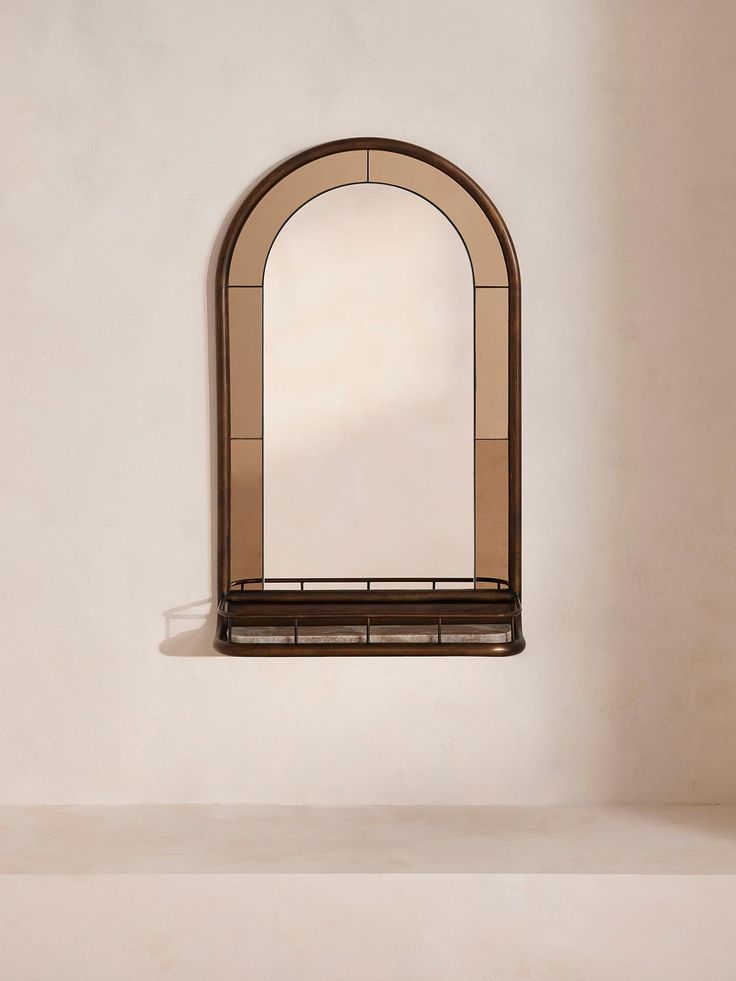 a mirror sitting on top of a shelf next to a white wall with a window