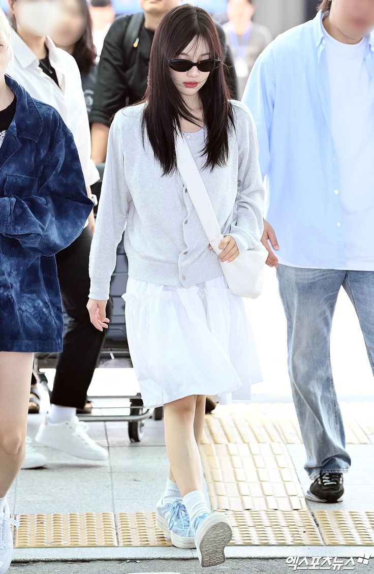 a woman walking down the street wearing sunglasses