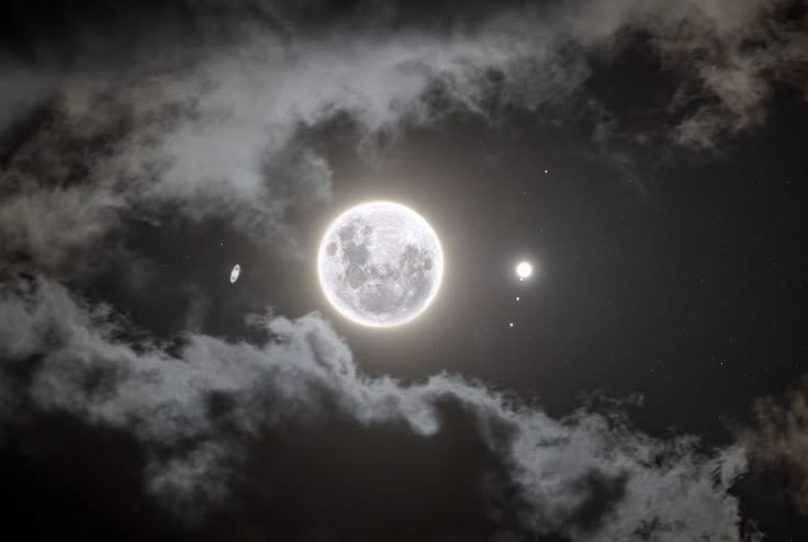 the moon and three planets are visible in the night sky with some clouds around them