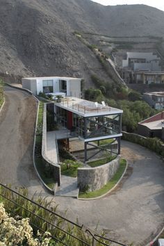 an aerial view of a house in the middle of a hilly area with mountains behind it