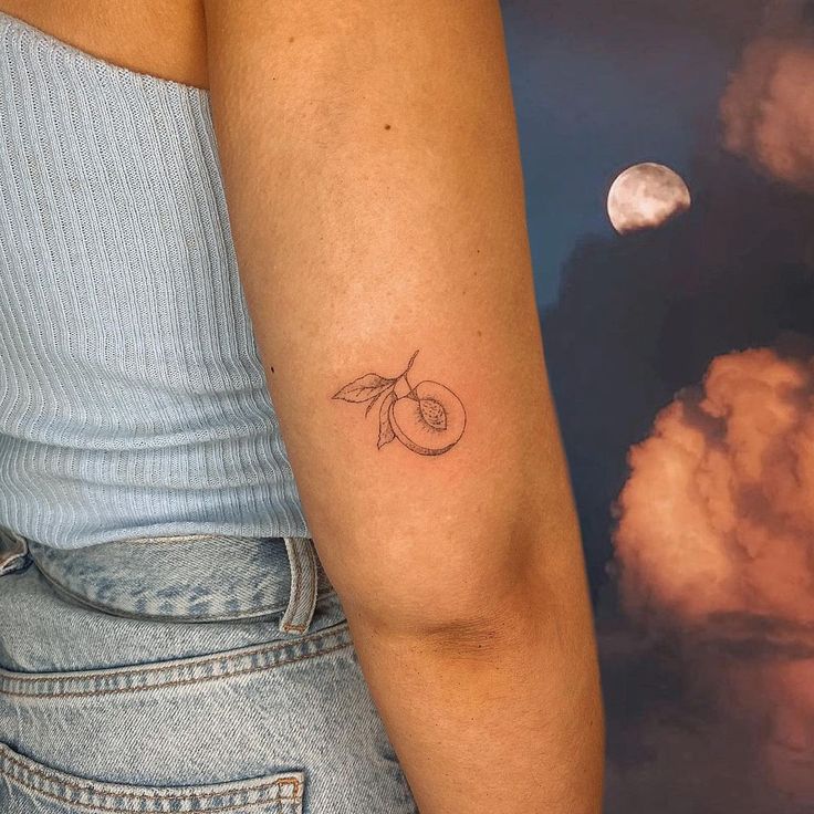 a woman's arm with a small cherry tattoo on the left side of her arm