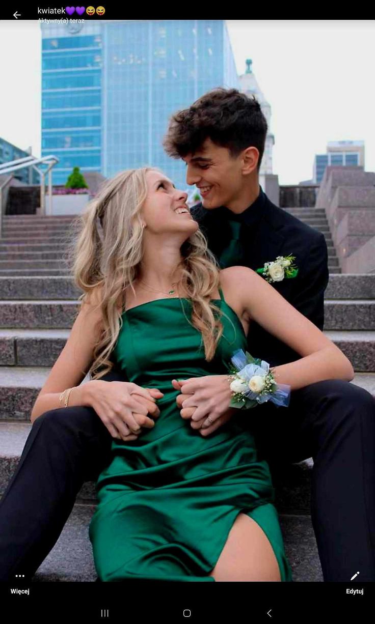 a man and woman are sitting on the steps together in front of some stairs with their arms around each other