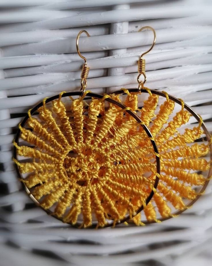 a pair of earrings that are sitting on a wicker basket in front of a white wall