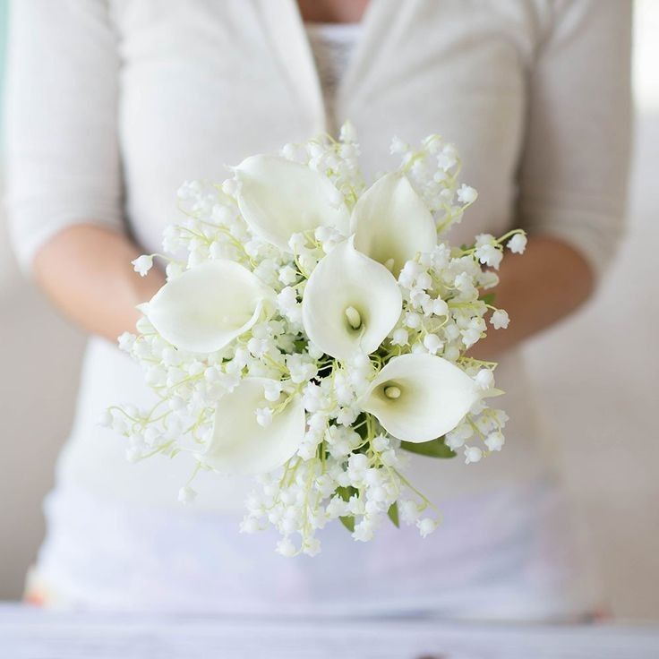 a woman holding a bouquet of white flowers