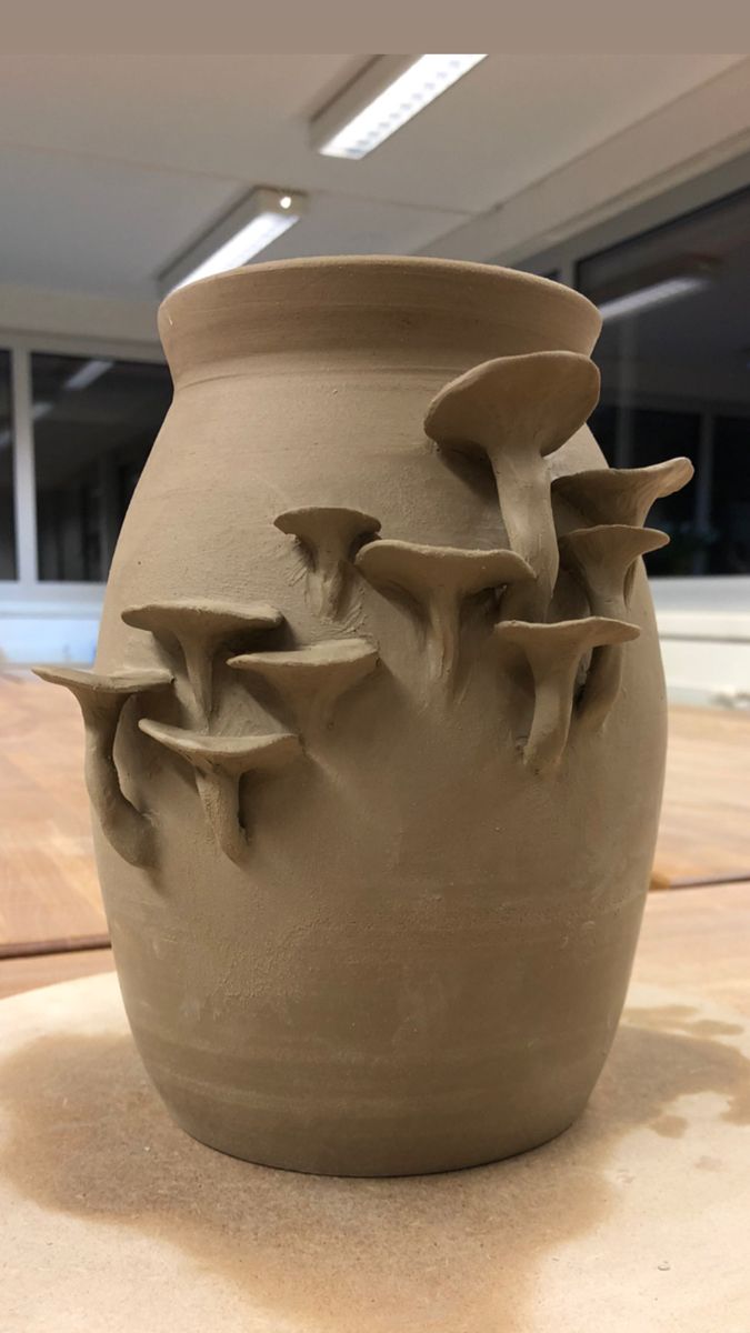 a clay vase sitting on top of a wooden table