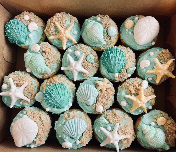 a box filled with cupcakes covered in blue frosting and sea themed decorations