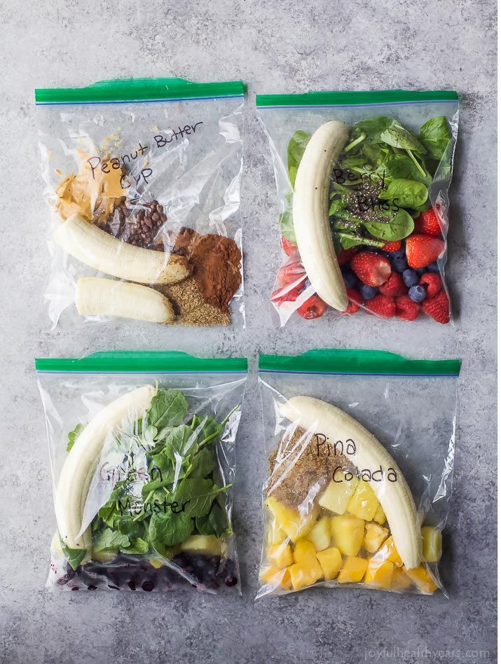 four plastic bags filled with different types of fruits and veggies on top of each other