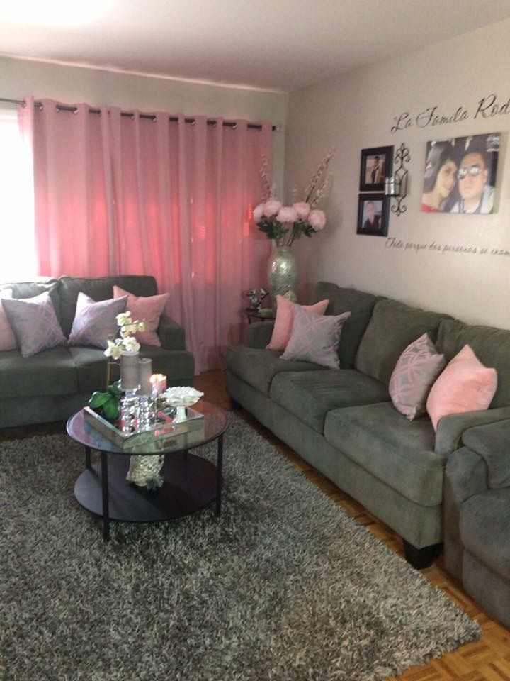 a living room with grey couches and pink curtains