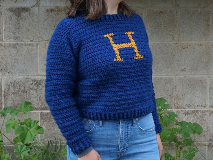 a woman wearing a blue sweater with the letter h on it