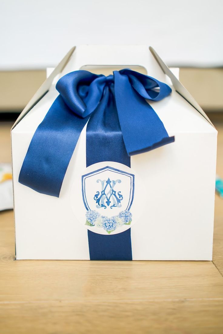 a white box with a blue ribbon and a crest on the front is sitting on a wooden table