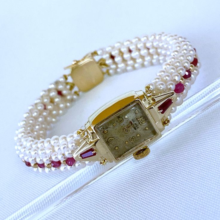 Beautiful One of A Kind stunning vintage working Winding Dial Watch is reworked into a timeless and elegant Pearl, Ruby and 14k Yellow Gold piece. Stamped and made in all solid 14k Yellow Gold, this timeless watch is revived by Tapered Baguette Rubies set on each side which perfectly contrasts the 14k Yellow Gold. A stunning band of round white Seed Pearls, Faceted Rubies and solid 14k Yellow Gold findings are all intricately woven together to frame this vintage piece. This top of the band is wo Classic Yellow Gold Diamond Watch With Jubilee Bracelet, Timeless Yellow Gold Watch With Jubilee Bracelet, Timeless Yellow Gold Diamond Watch For Wedding, Timeless Yellow Gold Jewelry And Watches With Jubilee Bracelet, Timeless Yellow Gold Jubilee Bracelet Jewelry And Watches, Timeless Yellow Gold Jewelry With Jubilee Bracelet, Classic Formal Jewelry And Watches With 17 Jewels, Wedding Jewelry With Diamond Hour Markers, Elegant 14k Gold Watches For Evening