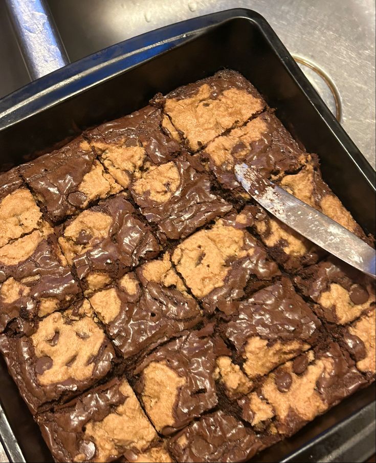 a pan filled with chocolate brownies and a spatula on top of the tray