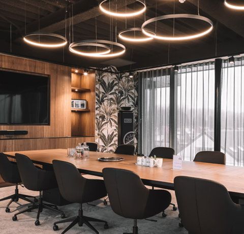 a large conference table with black chairs in front of a flat screen tv mounted on the wall