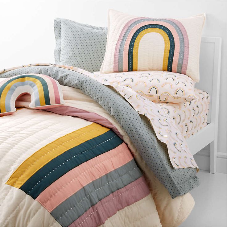 a bed with colorful comforters and pillows on it