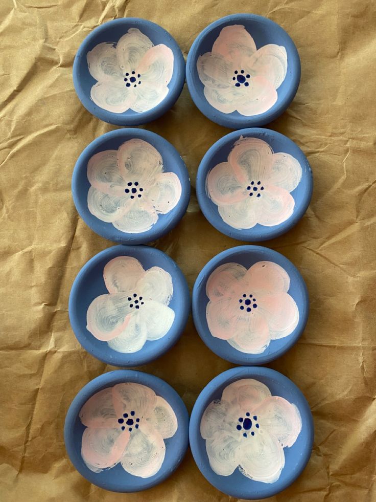 six blue bowls with white flowers in them on a brown tableclothed surface,