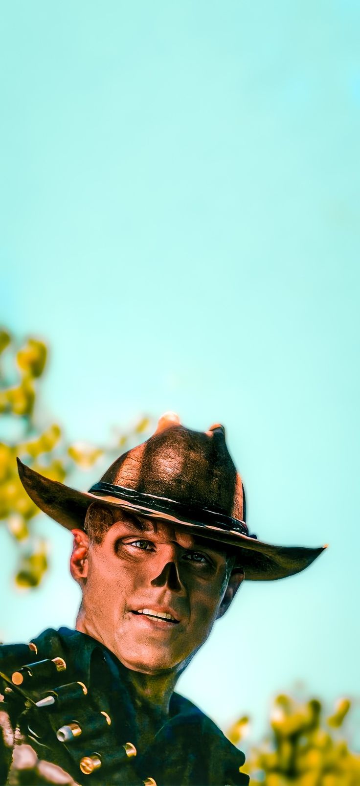 a man wearing a cowboy hat standing in front of some trees and yellow flowers on a sunny day