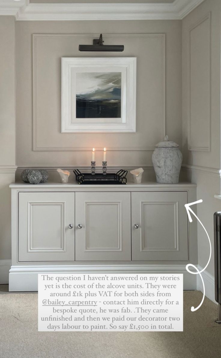 a white cabinet with two candles on it in a room that has beige walls and flooring