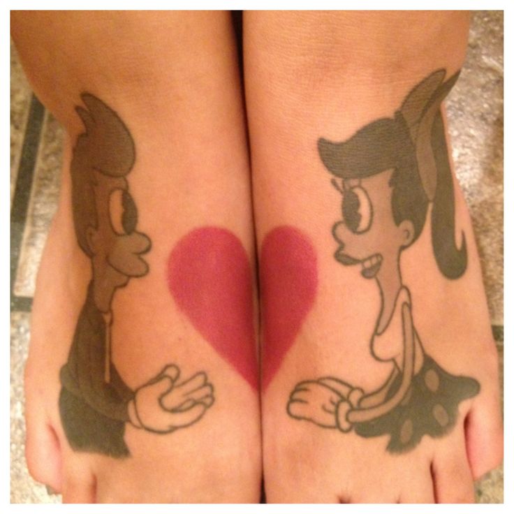 two people with tattoos on their legs holding a heart