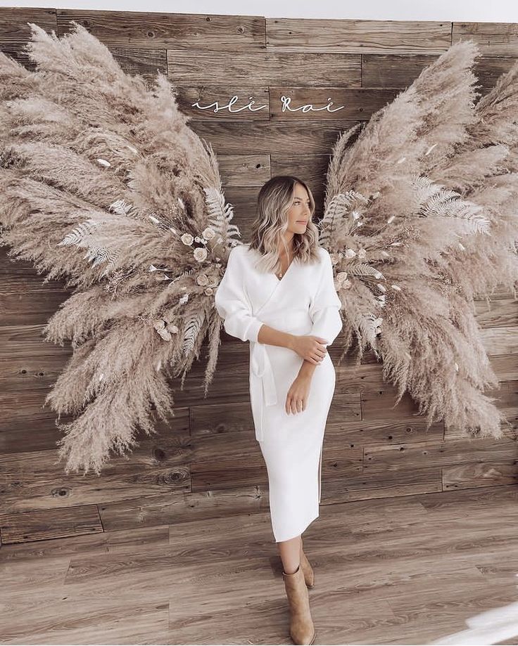 a woman standing in front of a wall with angel wings