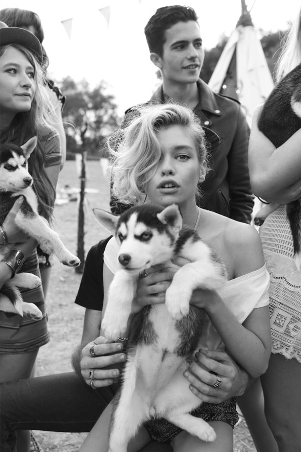 a group of people standing around each other holding husky puppies in their arms and looking at the camera