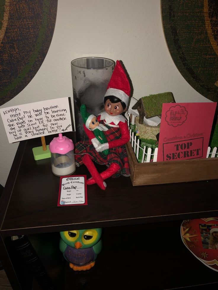 an elf doll sitting on top of a wooden table next to a sign and other items