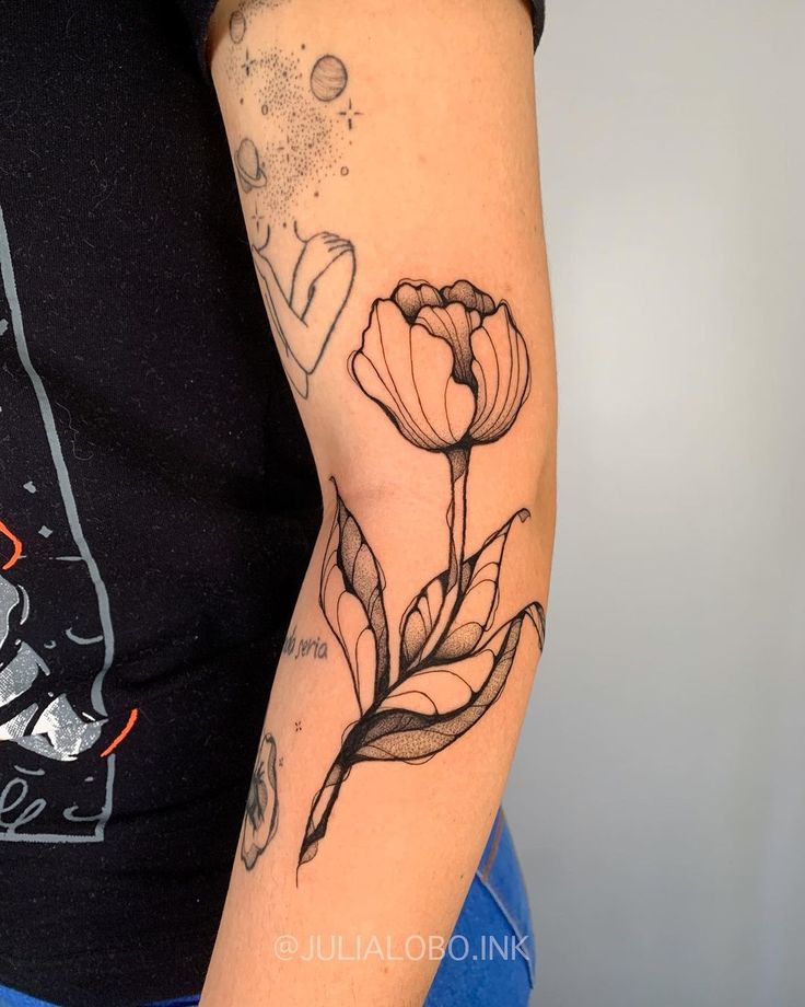 a woman's arm with a flower tattoo on the left side of her arm