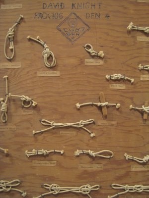 various ropes and knots are displayed on a wooden surface with words written in white ink