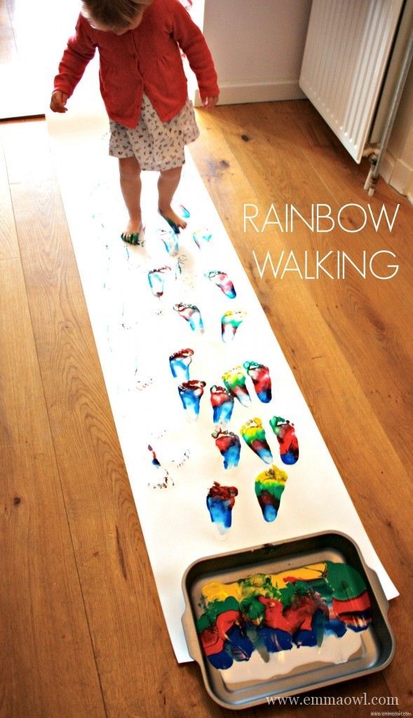 a toddler is standing on the floor in front of a tray with cupcakes