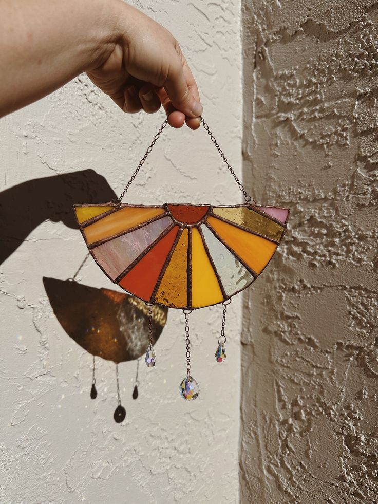 a hand holding a stained glass sun catcher