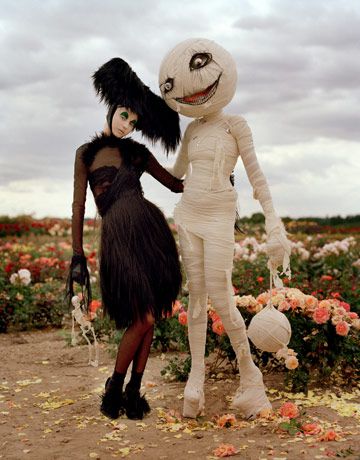 two people dressed in costumes standing next to each other with pumpkins on their heads