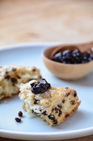 a white plate topped with two pieces of cake next to a bowl of raisins