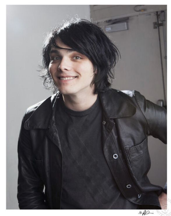 a young man with black hair wearing a leather jacket and looking at the camera smiling