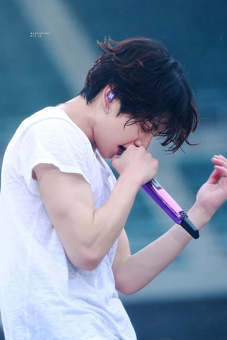 a young man holding a microphone in his right hand while wearing a white t - shirt