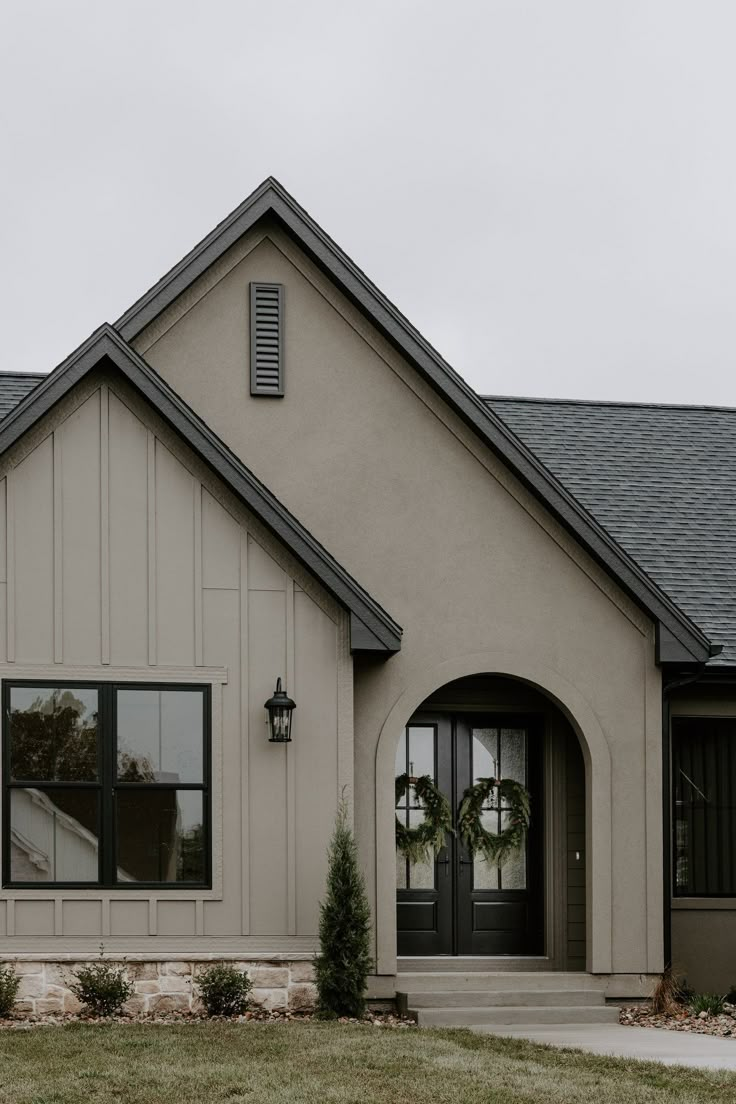 a gray house with two wreaths on the front door and one in the yard