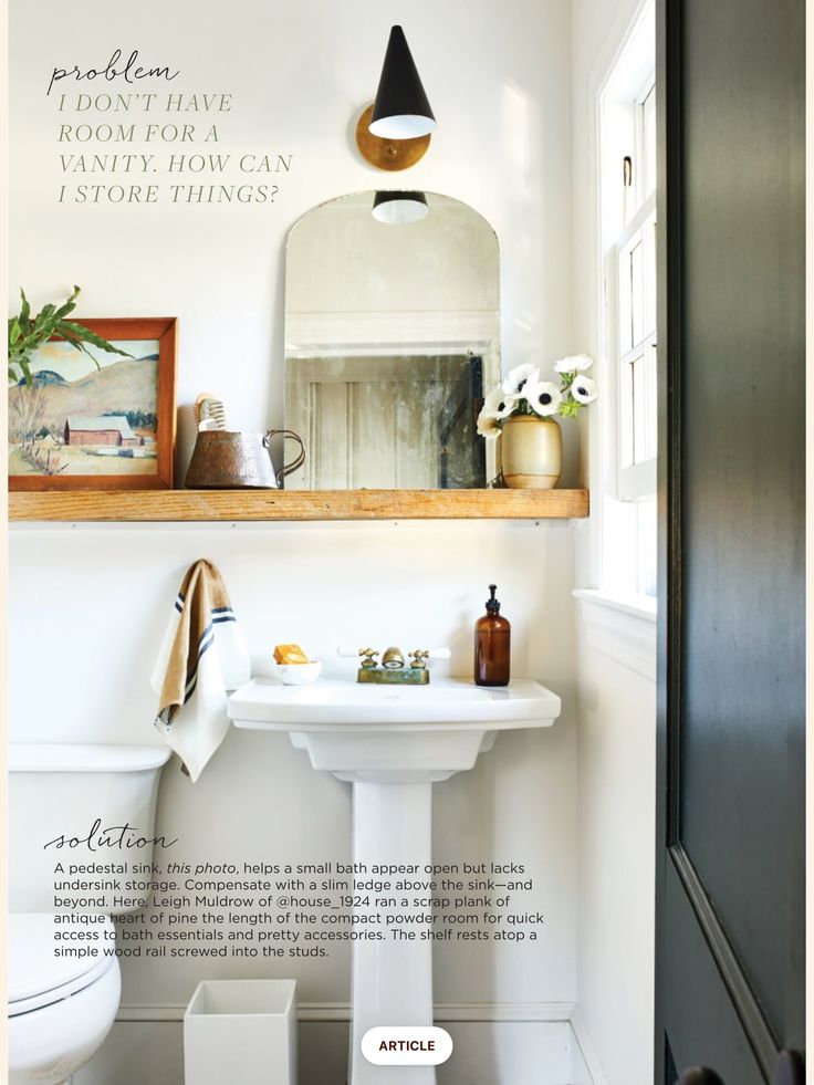 a white sink sitting under a bathroom mirror next to a wooden shelf filled with items