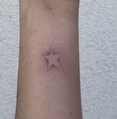 a small star tattoo on the wrist is shown in black ink, and it appears to be tiny