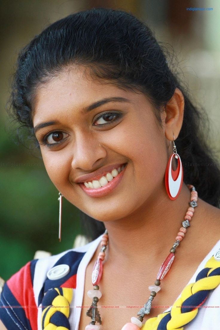 a smiling woman wearing colorful necklaces and earrings