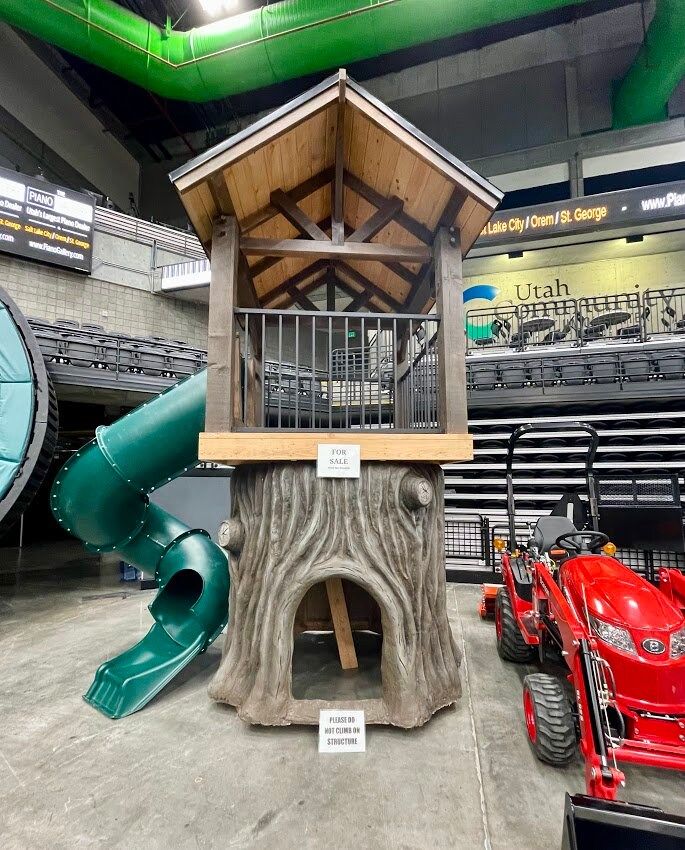 a tree stump with a slide in the middle of it and some seats behind it