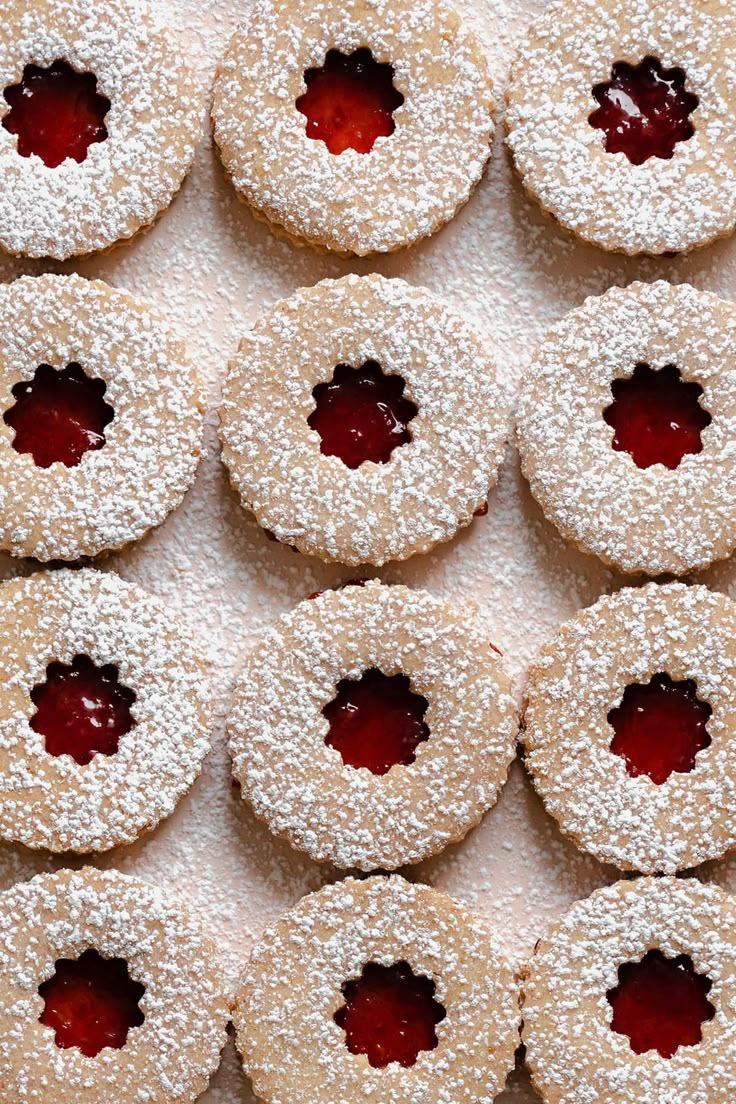 powdered sugar covered donuts with jam on them are arranged in a grid pattern