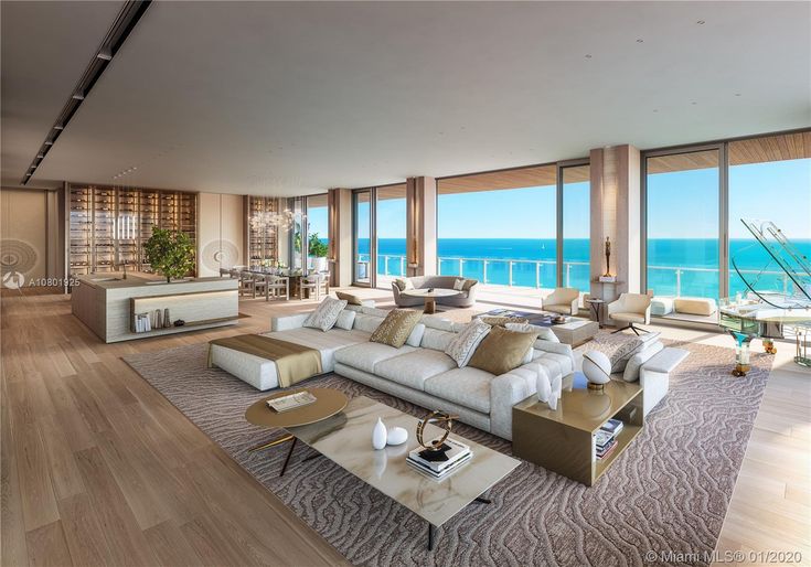 a living room filled with furniture and large windows overlooking the ocean in front of it