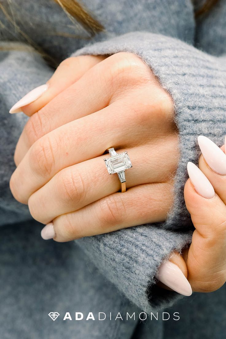 a woman's hand with a ring and manicured nails holding her engagement ring