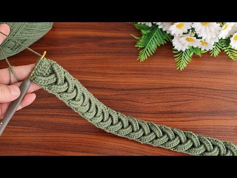 someone is crocheting the edge of a piece of green yarn with scissors on a wooden table