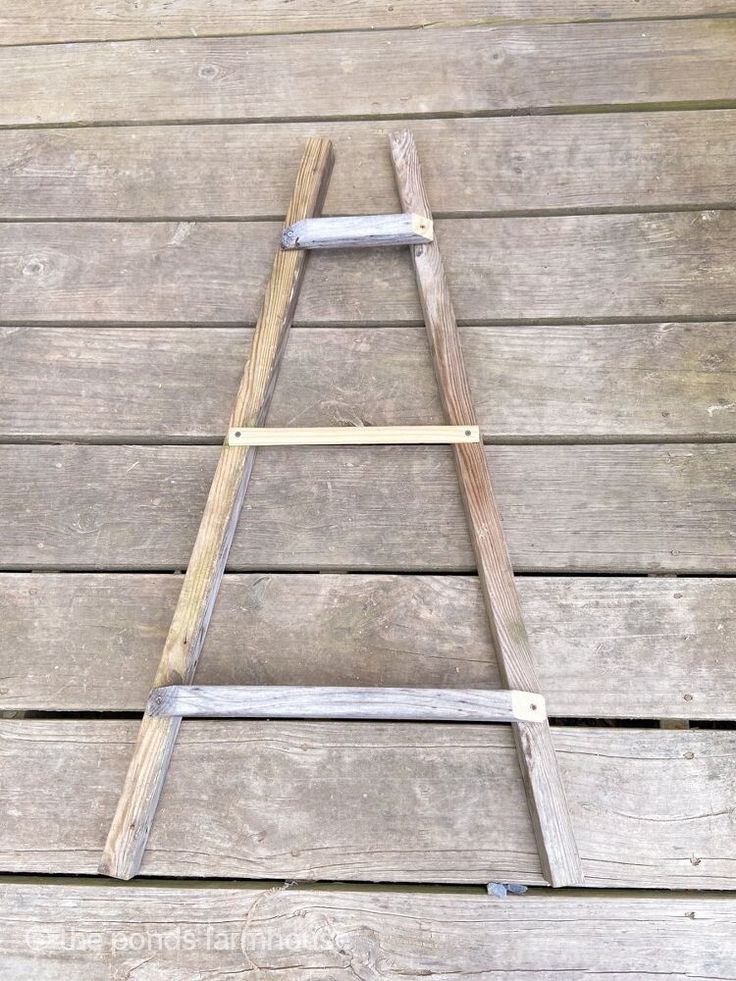 a wooden ladder sitting on top of a wooden floor next to a wall in the shape of a letter