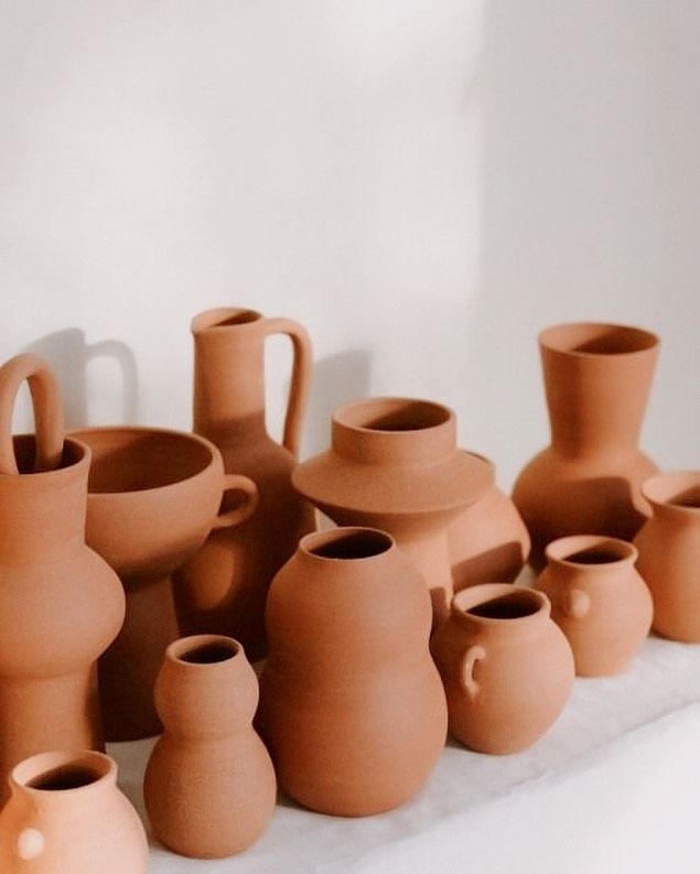 a group of clay vases sitting on top of a white tablecloth next to each other