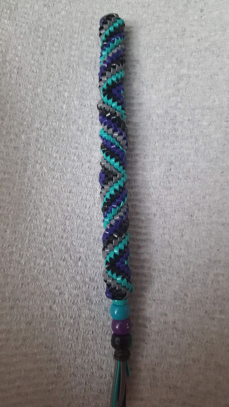 a close up of a cell phone holder on a white surface with blue and black beads