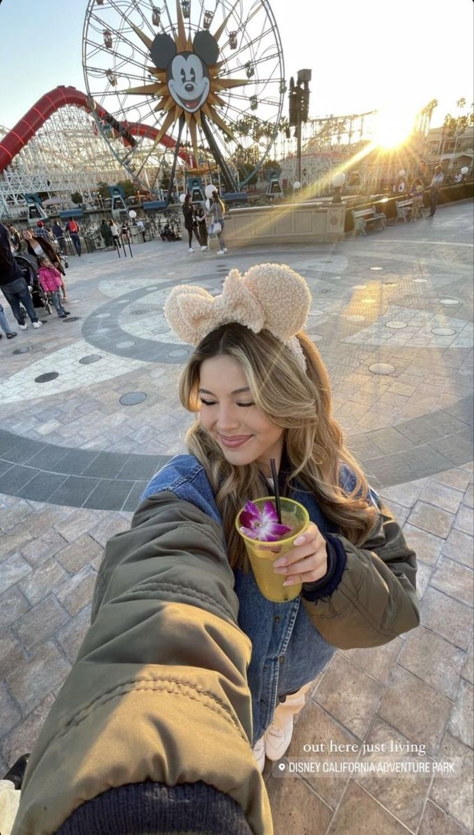 a woman holding onto her arm with a drink in front of an amusement park ferris wheel